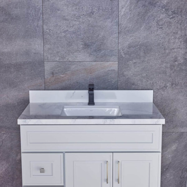 White bathroom vanity with marble countertop against gray stone wall.