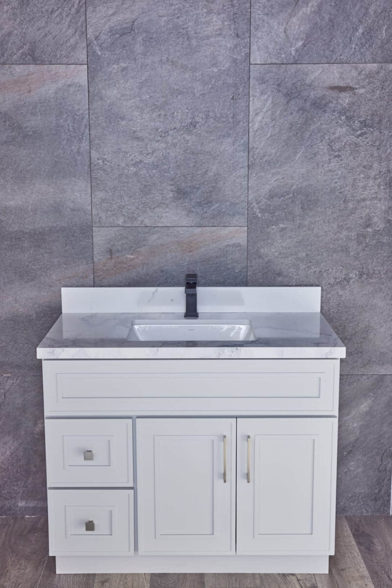 White bathroom vanity with marble countertop against gray stone wall.