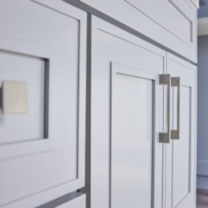 Close-up of modern white kitchen cabinets with sleek handles.