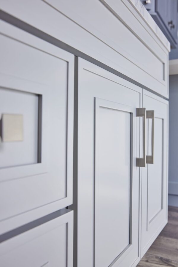 Close-up of modern white kitchen cabinets with sleek handles.