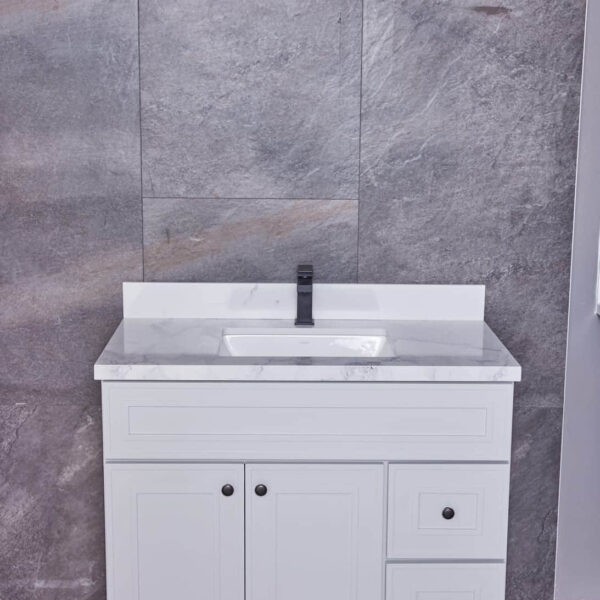 White bathroom vanity with marble countertop and gray tiled wall background.