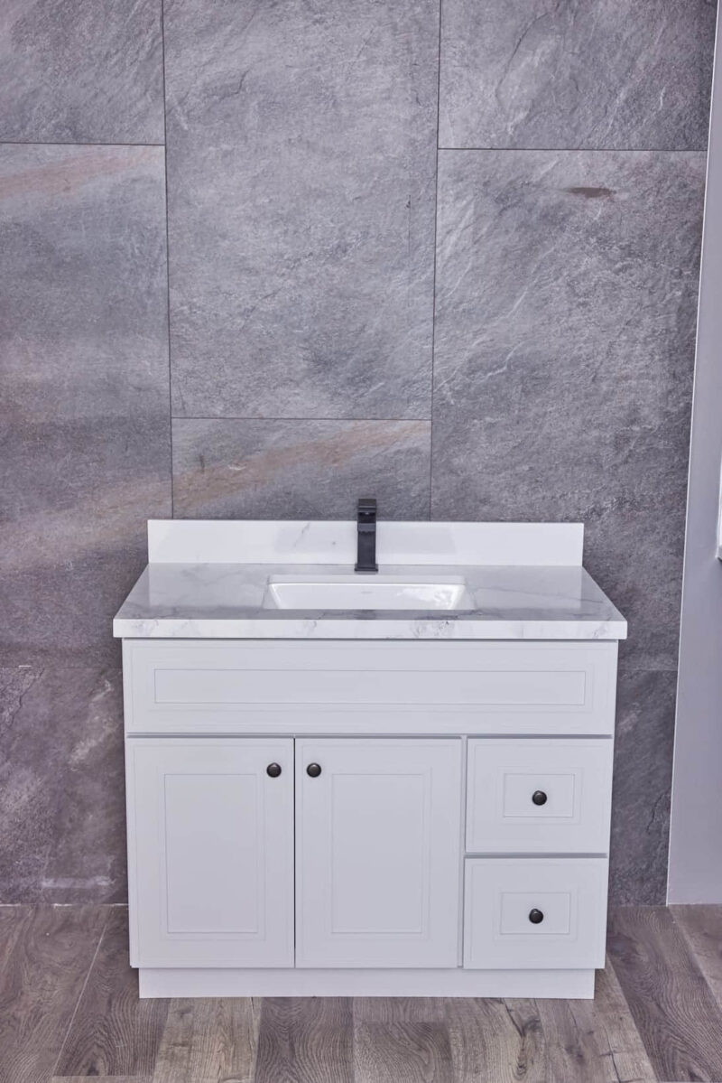 White bathroom vanity with marble countertop and gray tiled wall background.