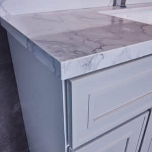 Marble countertop with modern faucet and light gray cabinet.
