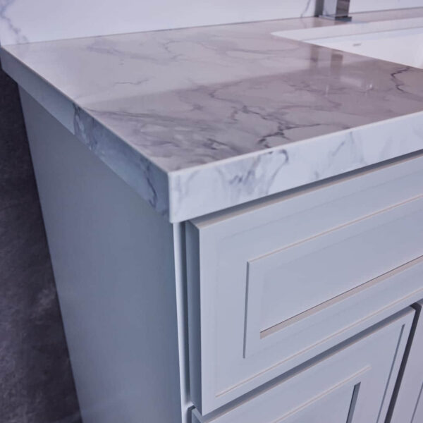Marble countertop with modern faucet and light gray cabinet.
