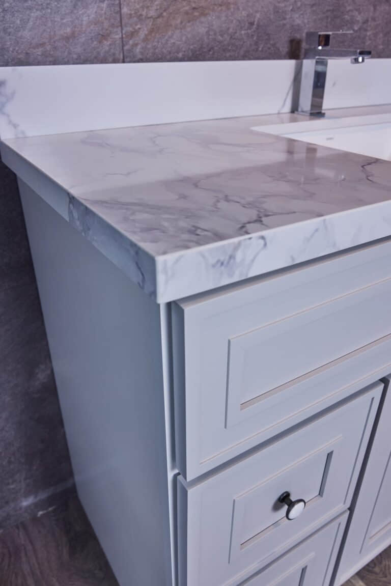 Marble countertop with modern faucet and light gray cabinet.
