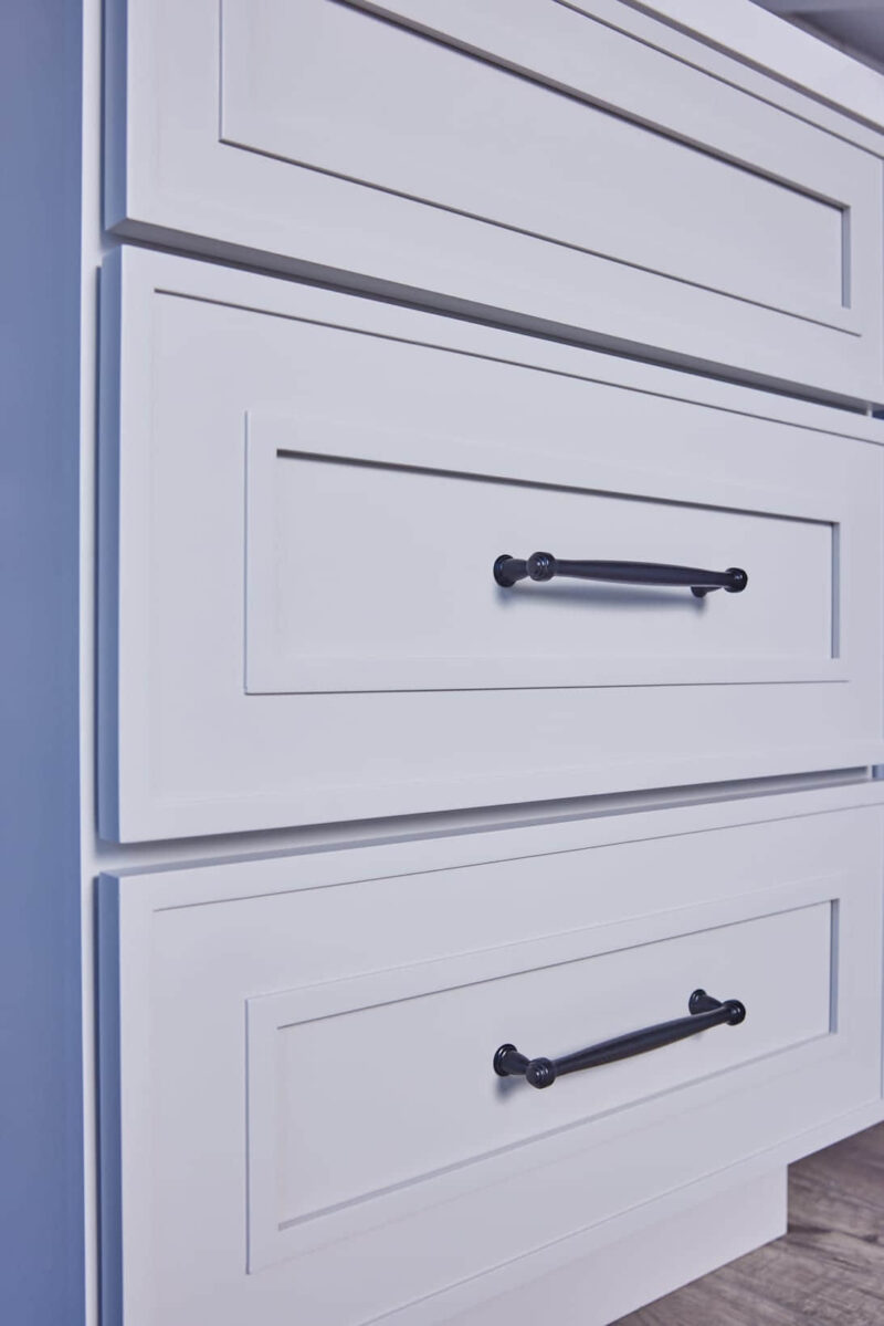 White kitchen cabinet with black handles.