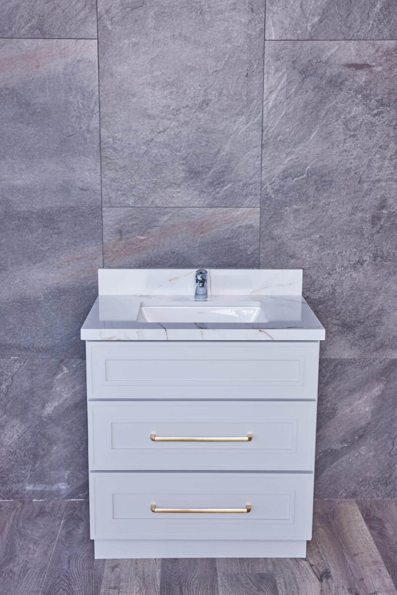 Modern bathroom vanity with marble countertop and gray tile background.