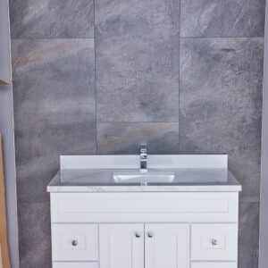 White bathroom vanity with marble countertop against gray tiled wall.