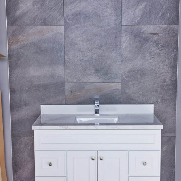 White bathroom vanity with marble countertop against gray tiled wall.