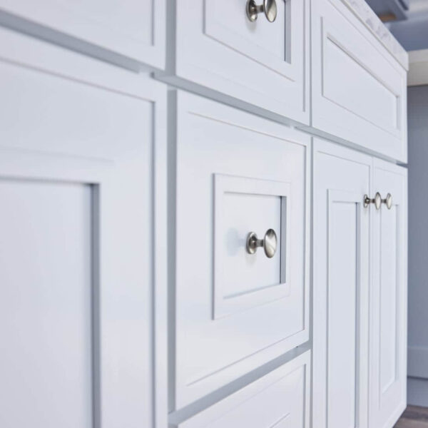 White kitchen cabinets with silver knobs.