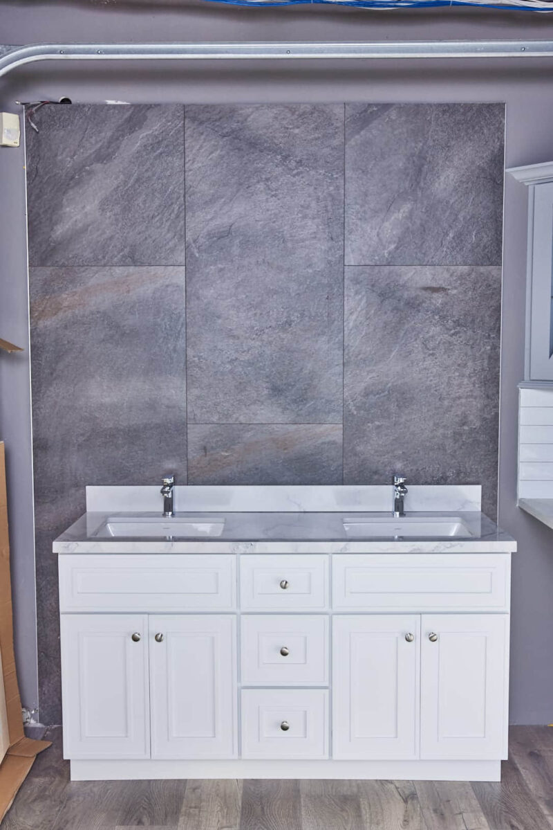 Double sink vanity with gray stone backsplash in modern bathroom.