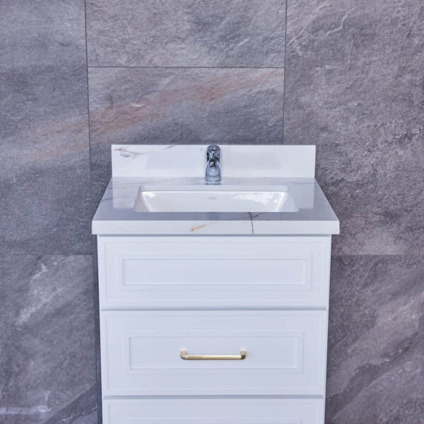 White bathroom vanity with marble countertop against gray tiled wall.