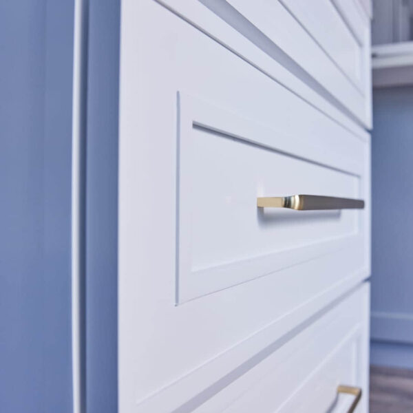 White kitchen cabinet with gold handles, close-up view.