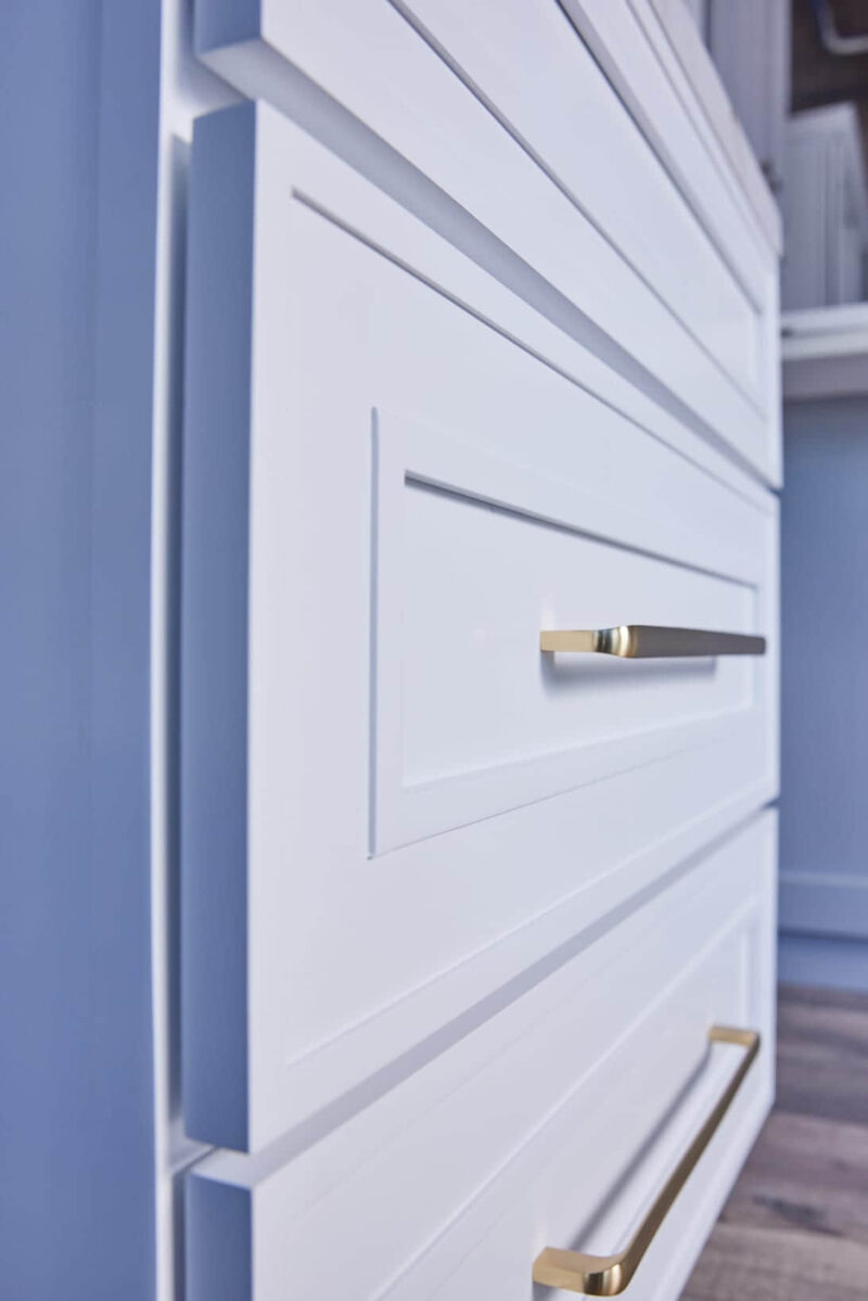 White kitchen cabinet with gold handles, close-up view.