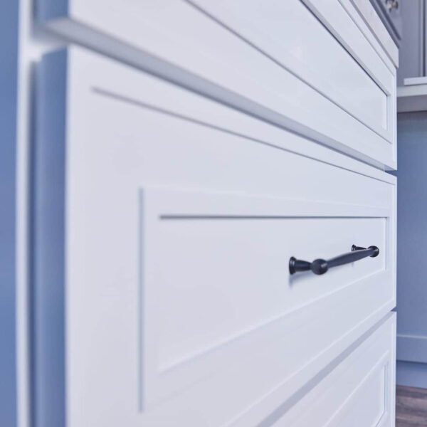 Close-up of white kitchen cabinets with black handles.