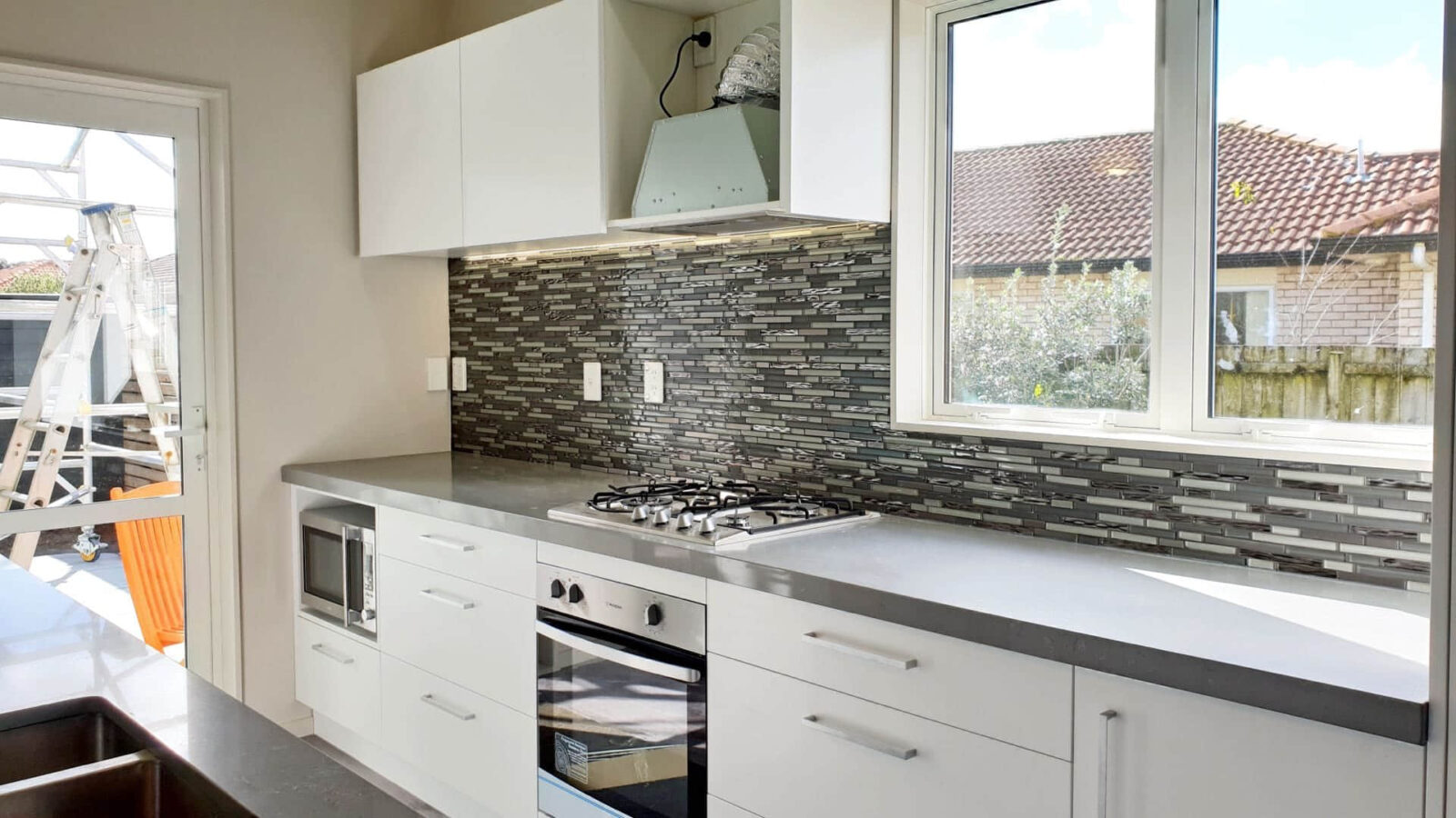 Modern kitchen with gray countertops and mosaic backsplash.