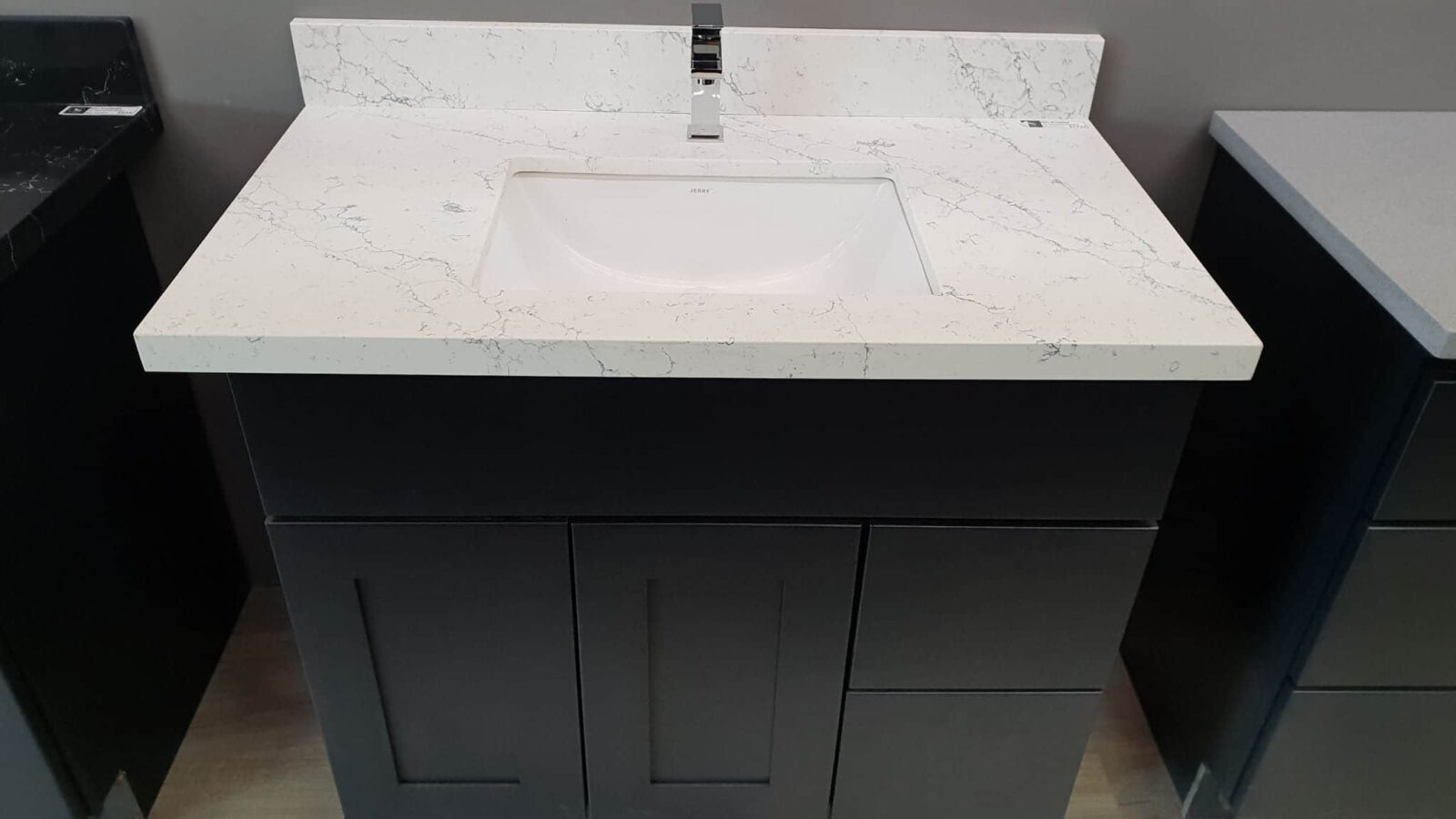 Modern bathroom vanity with white marble countertop and sleek black cabinet.