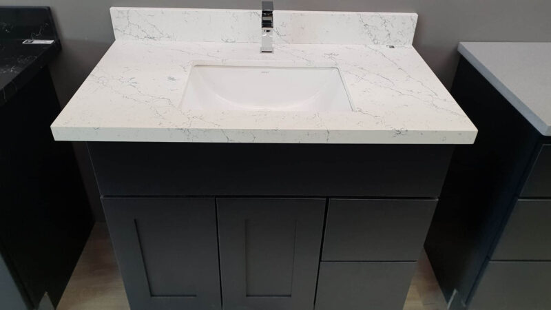 Modern bathroom vanity with white marble countertop and sleek black cabinet.