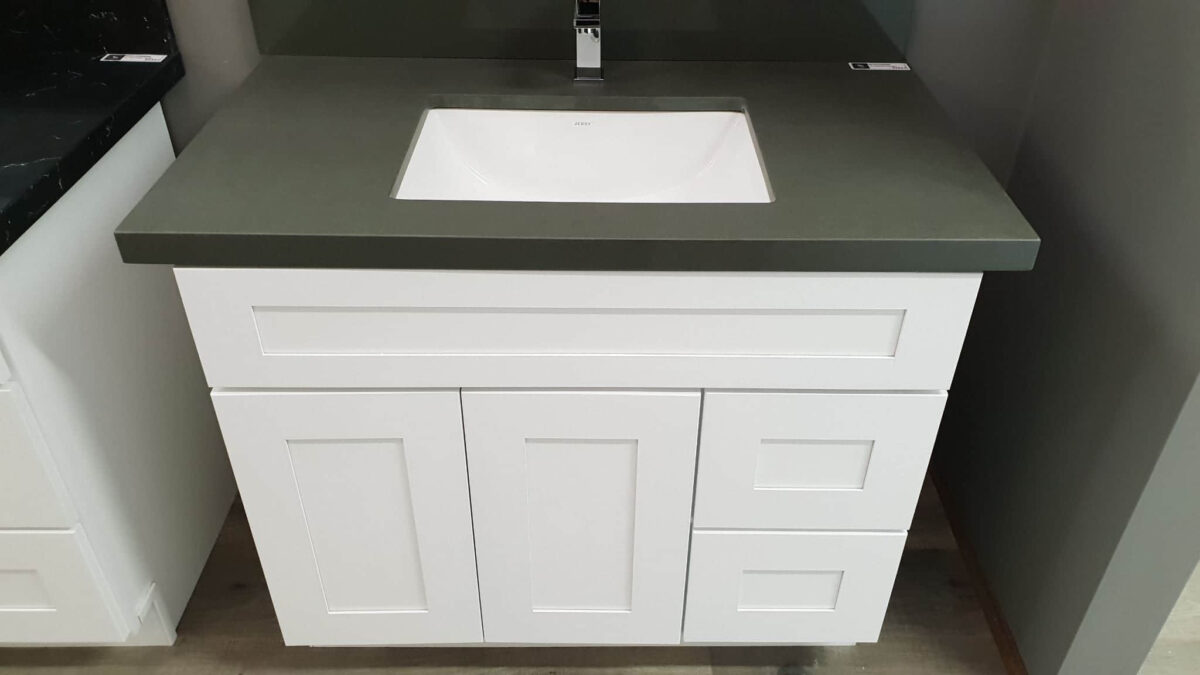 White bathroom vanity with green countertop and modern faucet.