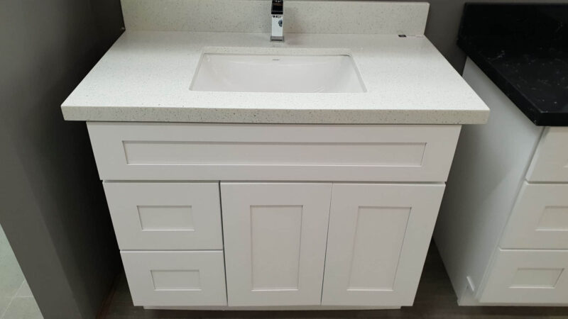 White bathroom vanity with sink and faucet.