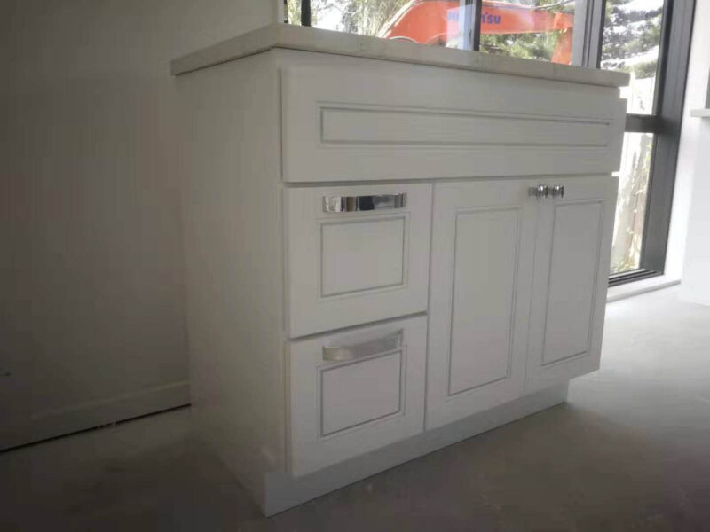 White kitchen cabinet with drawers and countertop in a bright room.