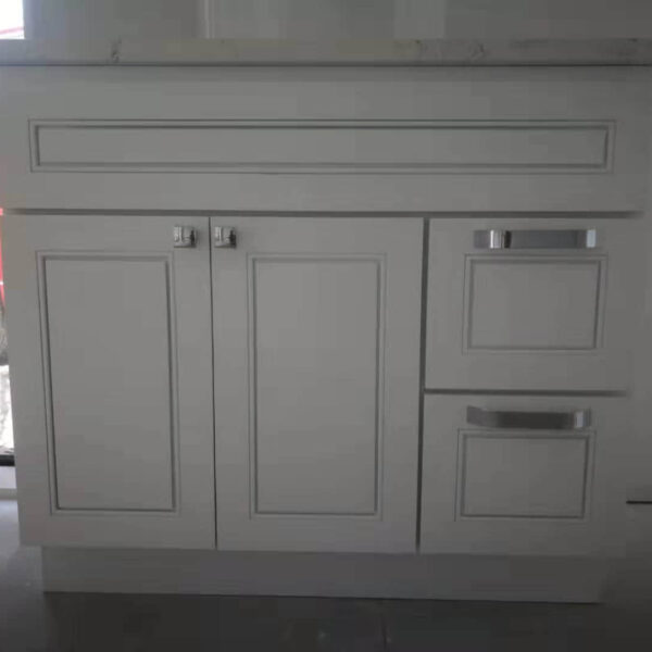 White kitchen cabinet with drawers and doors, against a window.