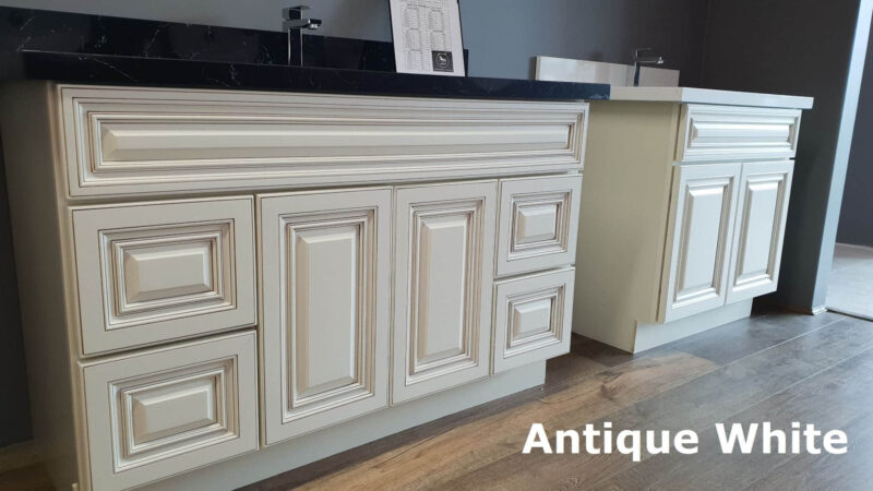 Antique White kitchen cabinets with intricate panel design and dark countertop.
