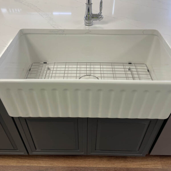 Farmhouse kitchen sink with grid, set in a marble countertop.