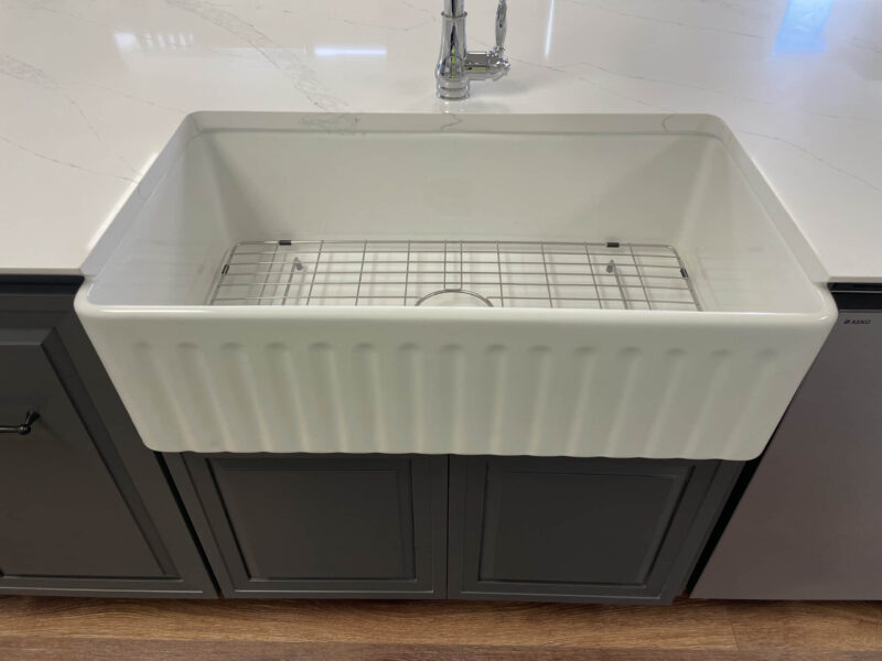 Farmhouse kitchen sink with grid, set in a marble countertop.