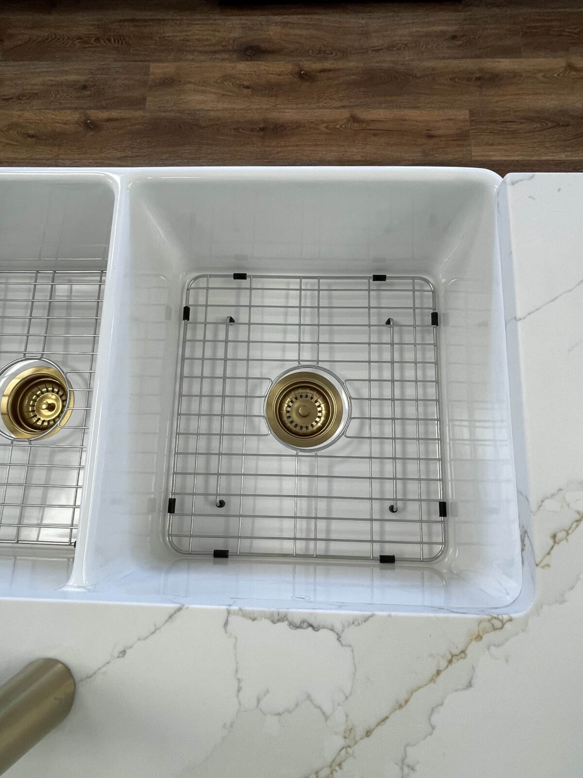 White kitchen sink with metal grid and drain.