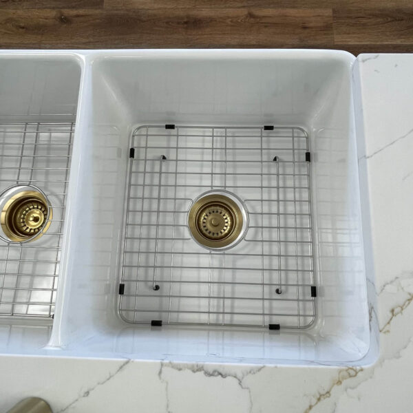 White kitchen sink with metal grid and drain.