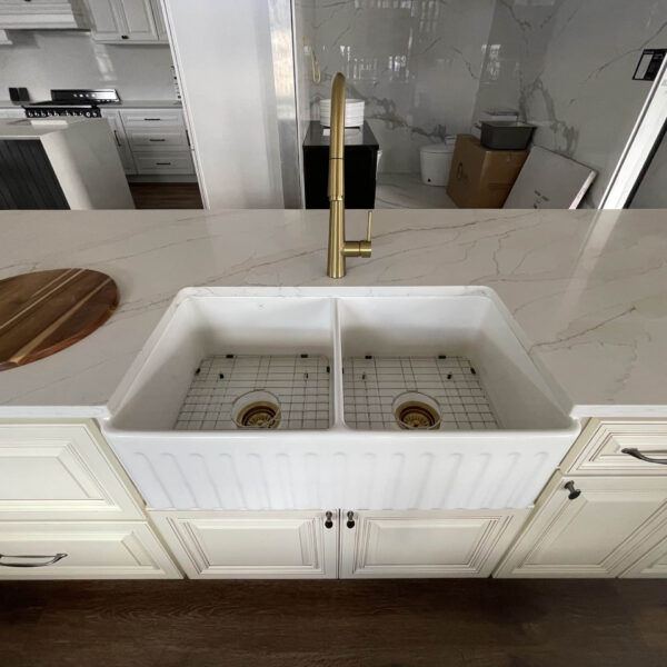 Modern kitchen with marble countertop and double farmhouse sink.
