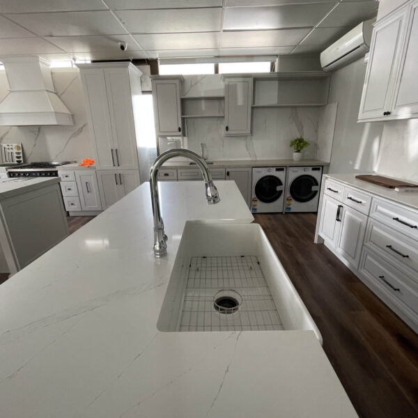 Modern kitchen with white cabinetry, island sink, and laundry appliances.