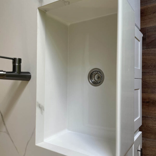 White kitchen sink with modern faucet on wooden countertop.