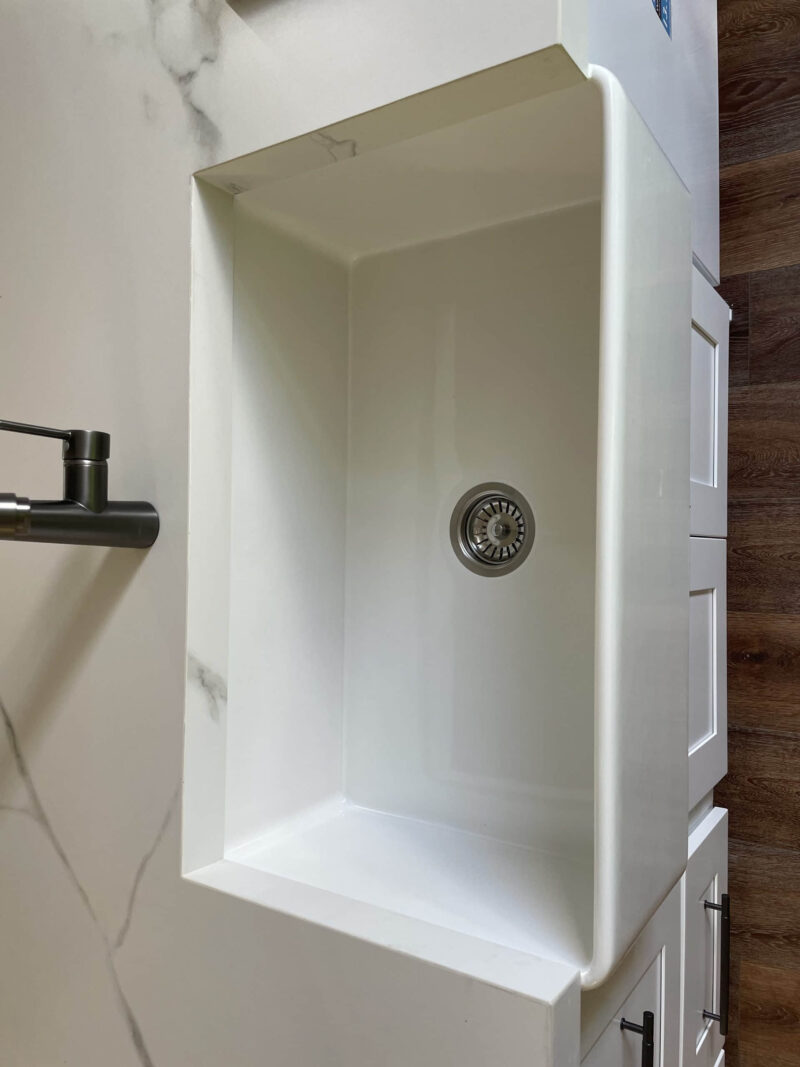 White kitchen sink with modern faucet on wooden countertop.