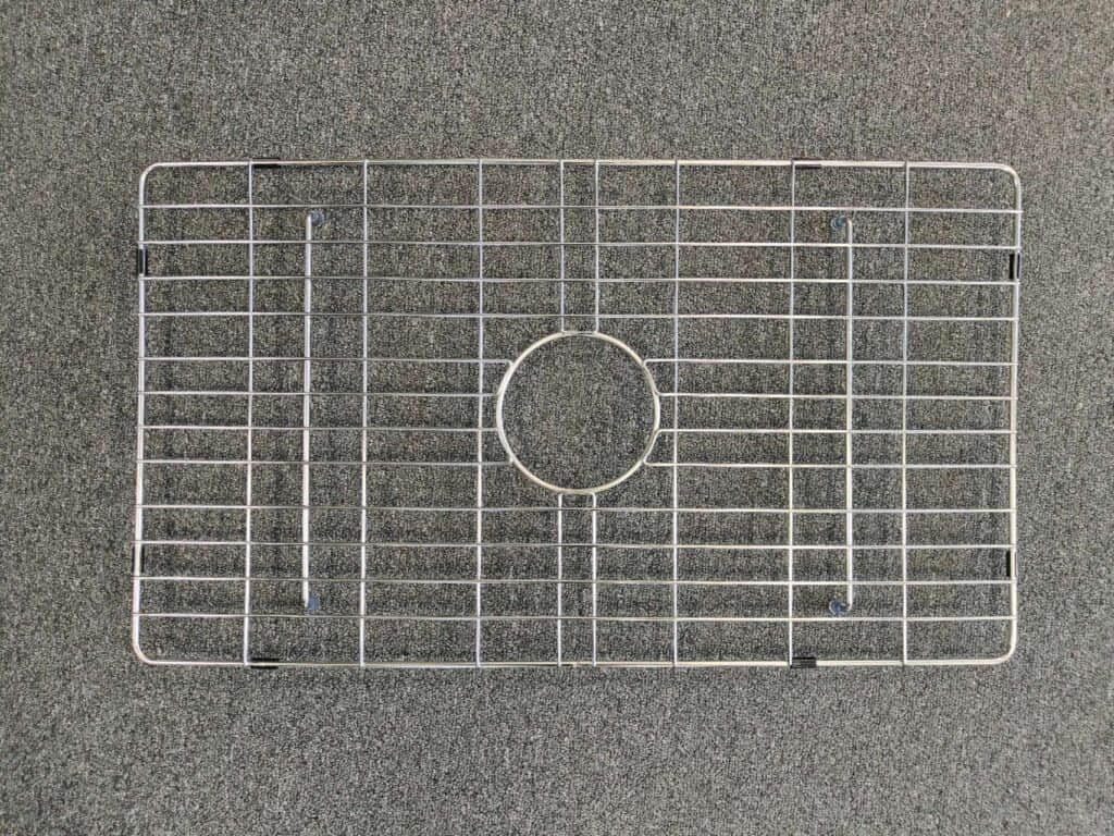 Metal sink protector on a gray surface.