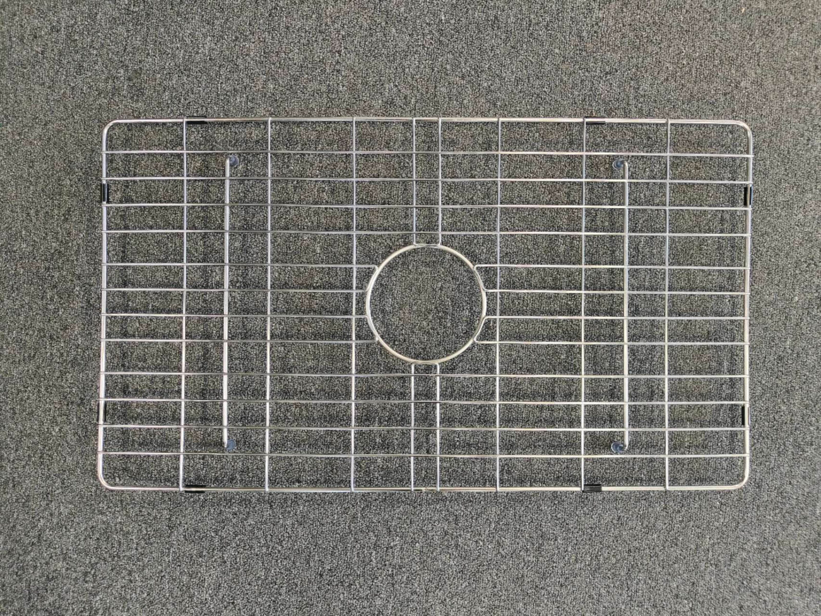 Metal sink protector on a gray surface.