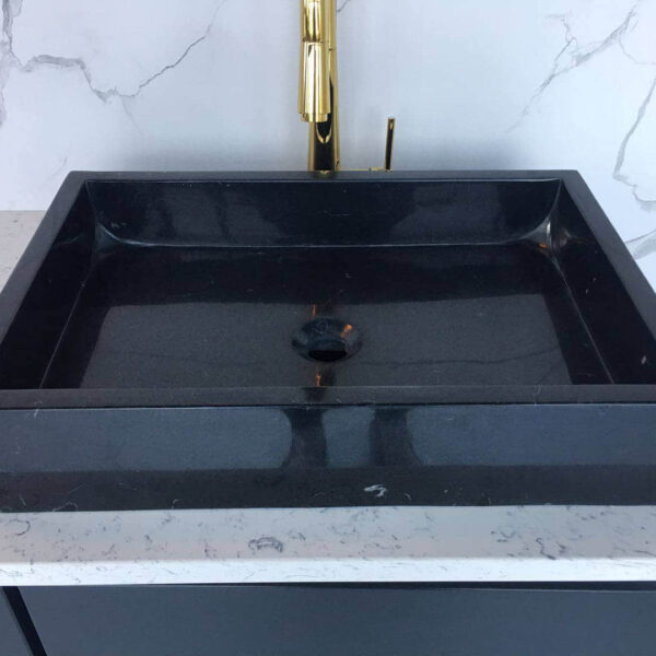 Black marble sink on a white marble countertop.