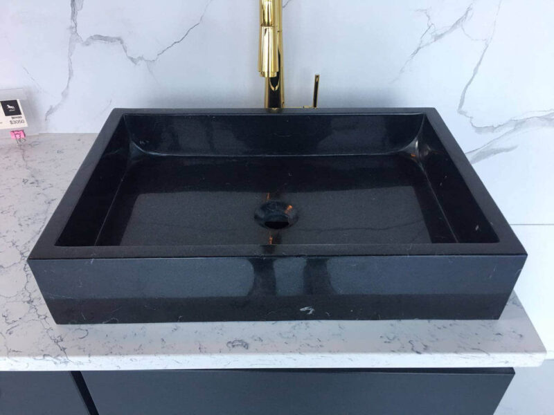 Black marble sink on a white marble countertop.
