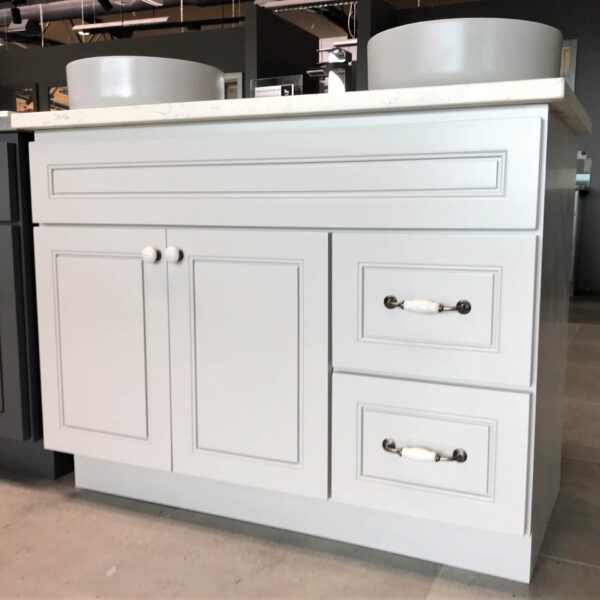 Light gray kitchen cabinet with drawers and round handles.