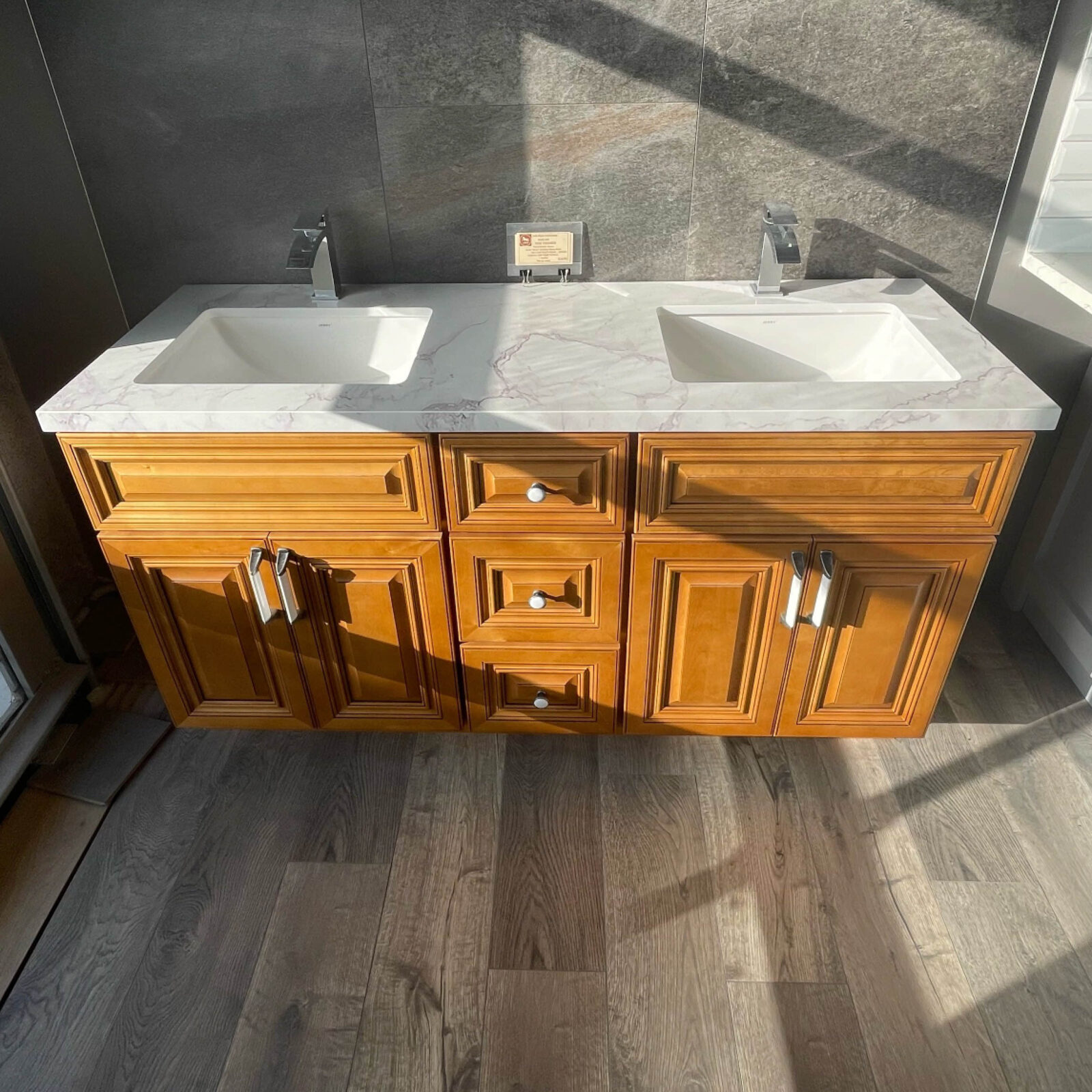 Wooden double sink vanity with marble countertop in a sunlit bathroom.