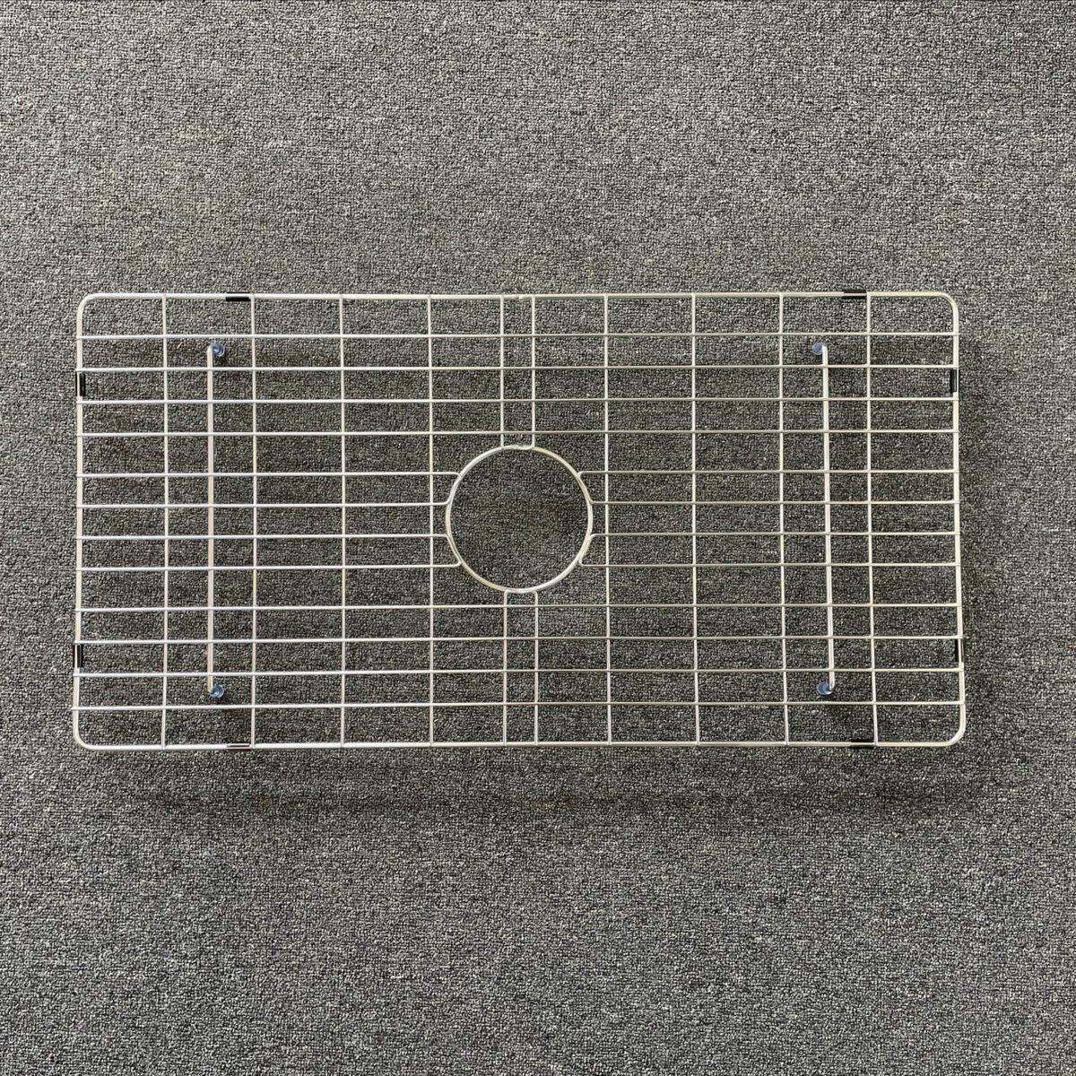 SingleL-1-scaled-2.jpg Stainless steel sink grid on a textured surface.