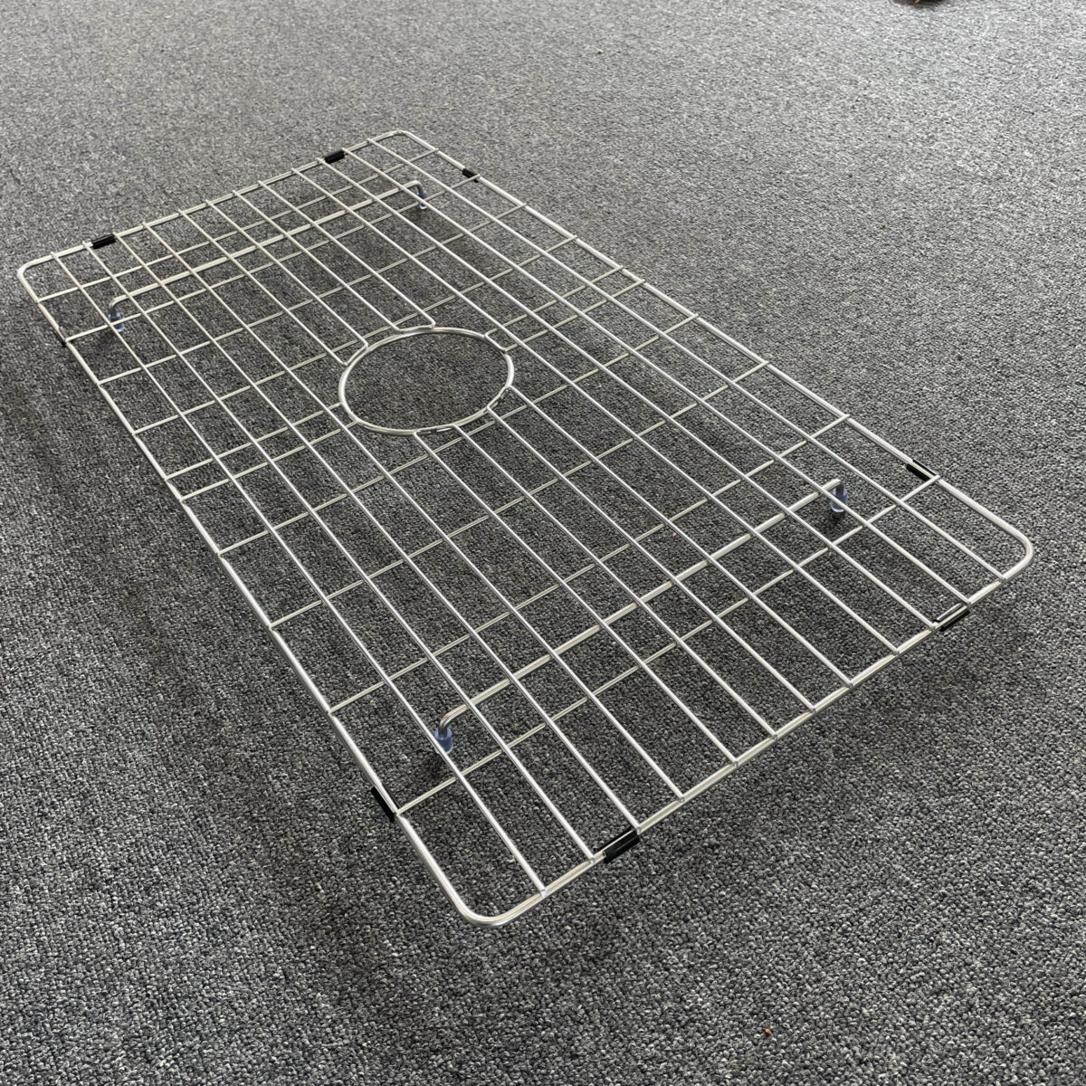 Stainless steel sink grid on gray carpet.