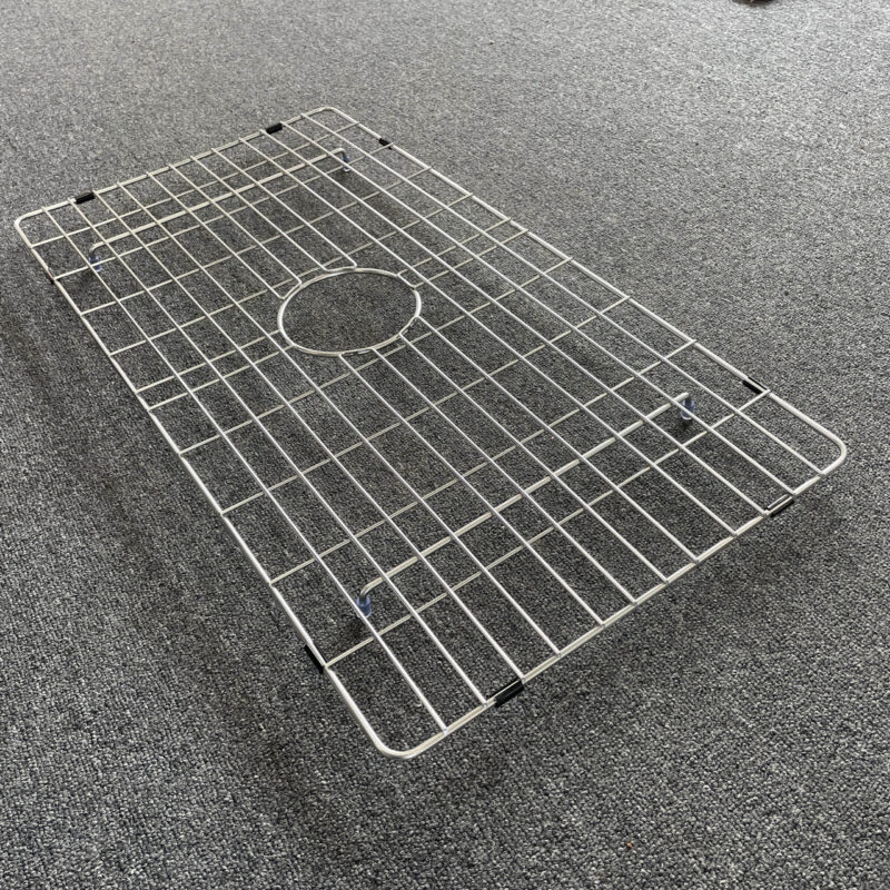 Stainless steel sink grid on gray carpet.