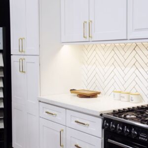 Modern kitchen with white cabinets and herringbone backsplash.