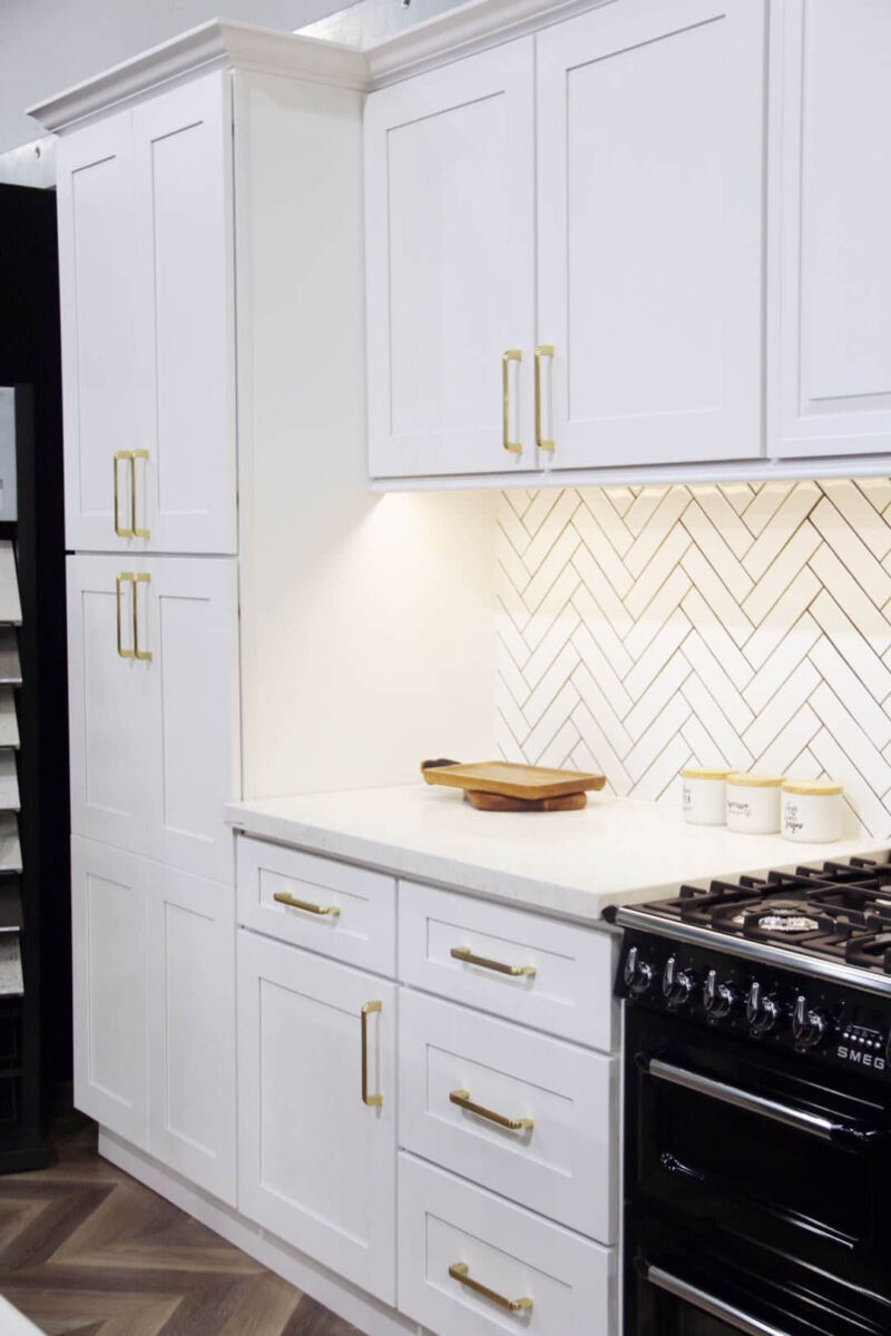 Modern kitchen with white cabinets and herringbone backsplash.