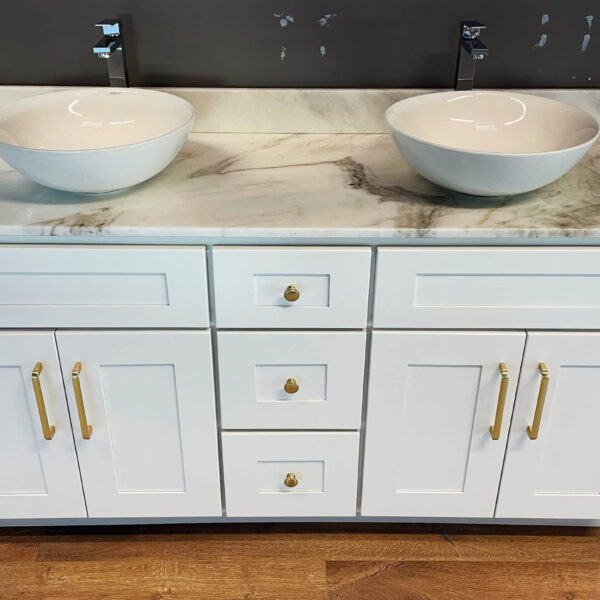 White marble double sink vanity with gold handles on wooden floor.