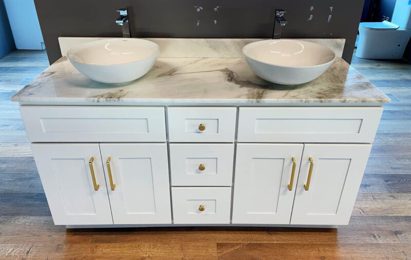 White marble double sink vanity with gold handles on wooden floor.