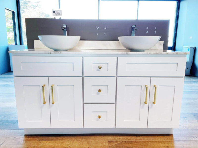 White bathroom vanity with dual sinks and gold handles.