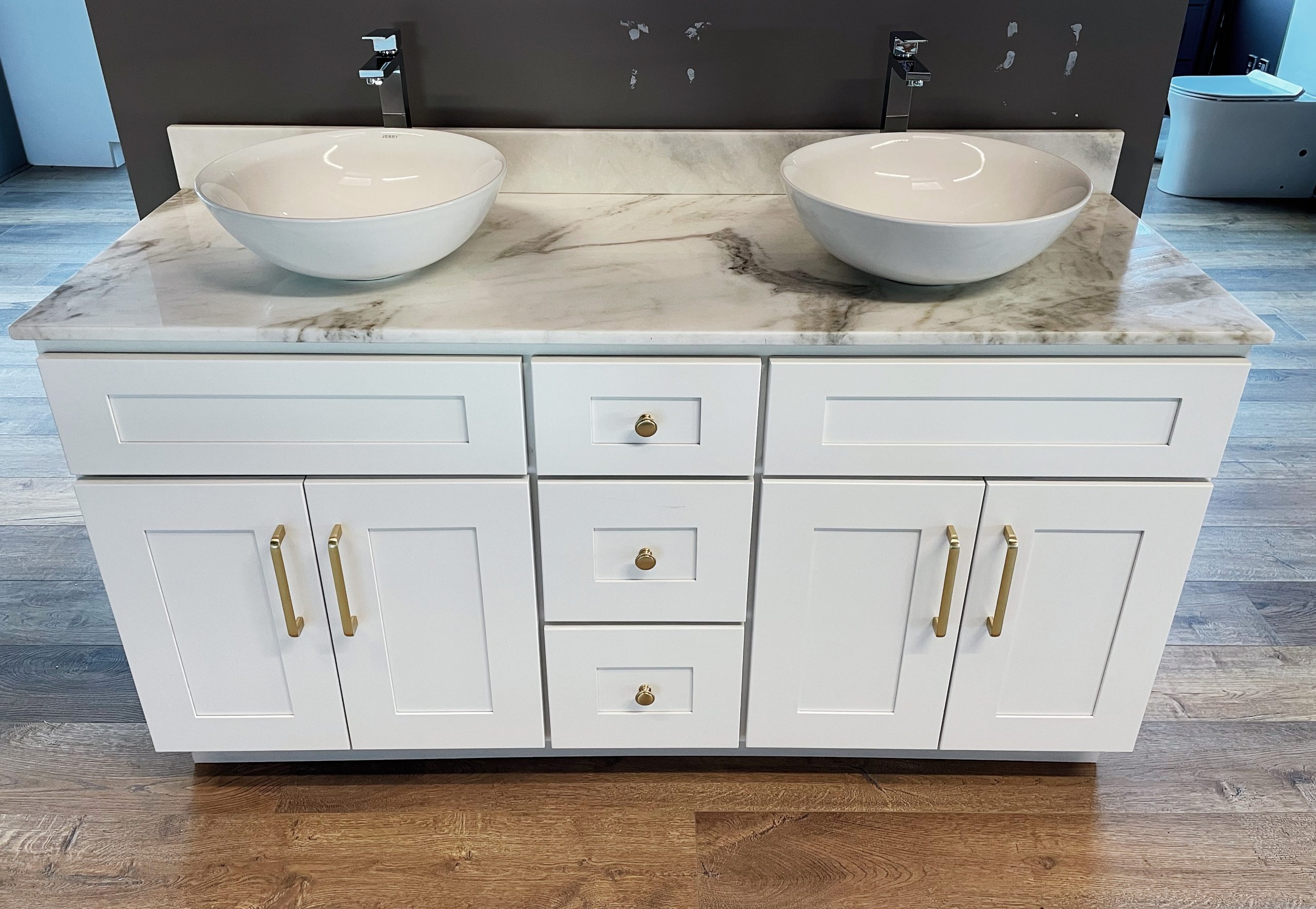 White marble double sink vanity with gold handles on wooden floor.